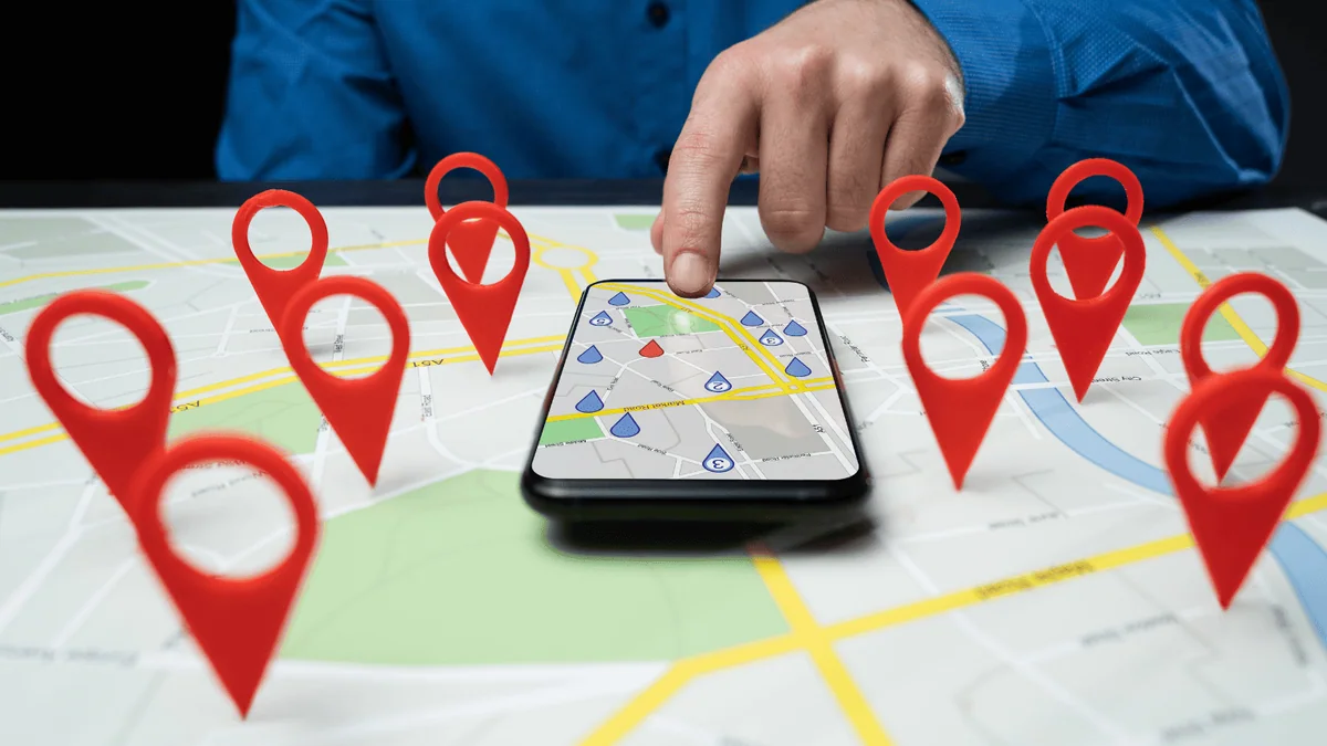 Mapa con pines de ubicación y un teléfono móvil para representar el SEO local